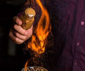 Bartender in purple shirt with flaming drink