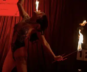 Performer eating fire with curtains in background